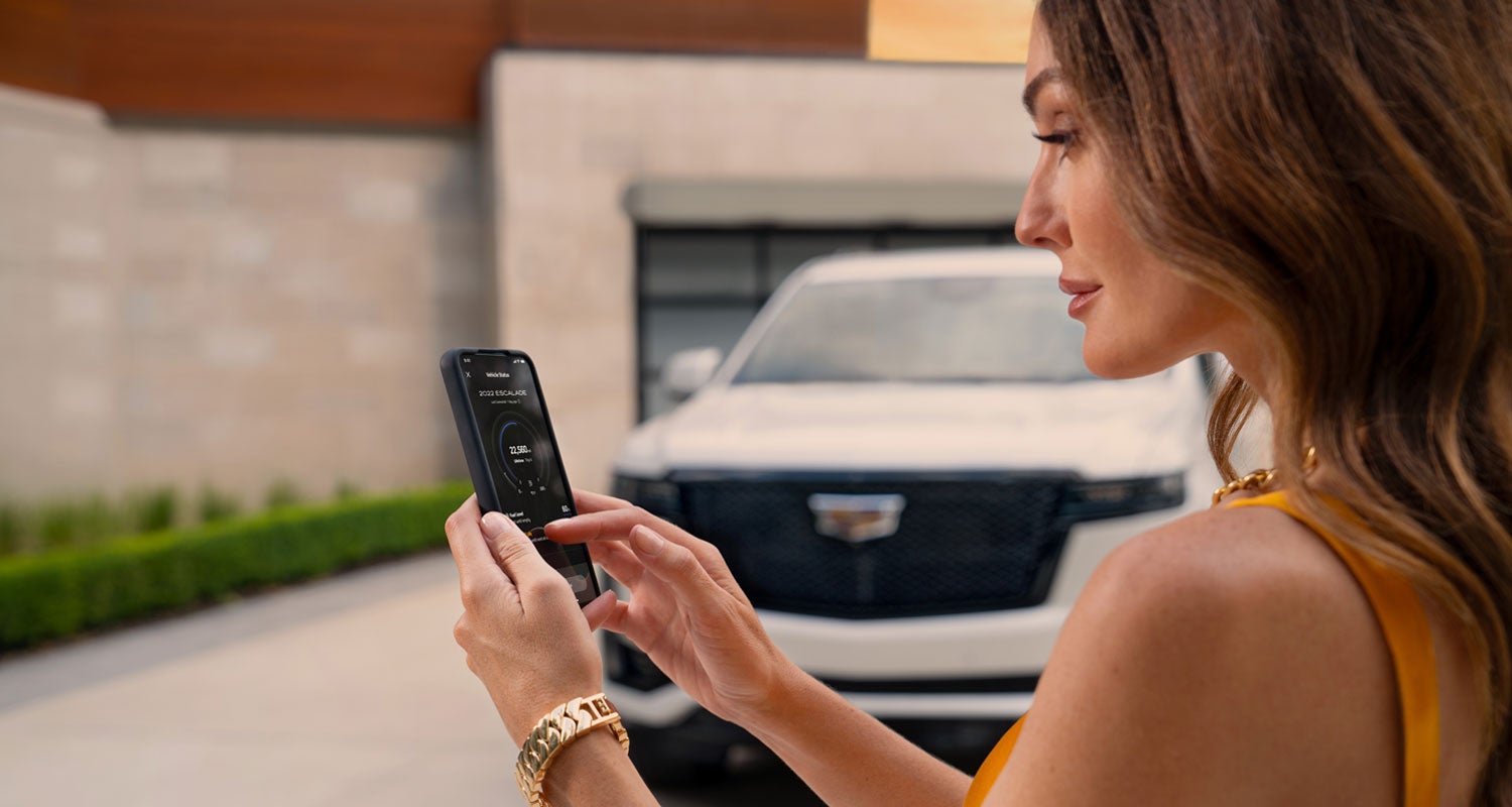 lady checking her mobile with a Cadillac vehicle background | Dossett Cadillac in HATTIESBURG MS